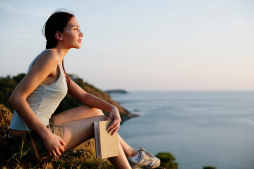 Woman sitting on rocks looking at ocean